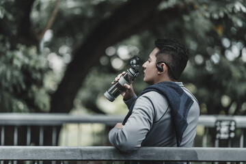 Young sport man listen music earphone and  drink water after jogging, running in the park. Sport...
