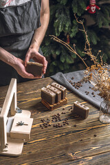 Women's hands cut coffee homemade natural soap on a professional wood cutter. A means of...