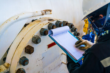 Engineer inspects large high pressure tanks in petroleum industry for maintenance.