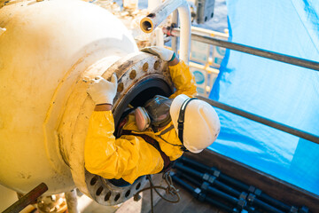 A high-pressure tank inspector enters a confined space in a petroleum chemical protective suit.