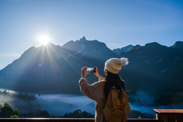 Young woman traveler taking a beautiful landscape at sunrise over the mountains, Travel lifestyle concept - obrazy, fototapety, plakaty