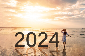 Young woman traveler looking beautiful sunset on the tranquil beach celebrating New Year 2024,...