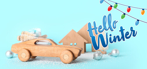 Composition with wooden car and Christmas decorations on light blue background. Hello winter