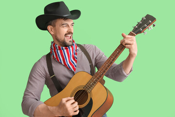 Handsome cowboy playing guitar on green background
