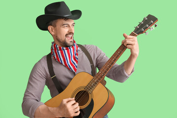 Obraz premium Handsome cowboy playing guitar on green background