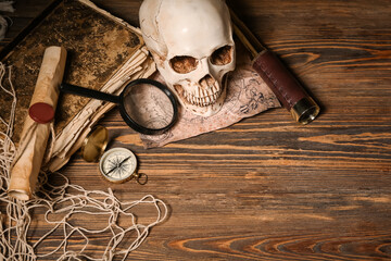 Human skull with old manuscripts, world map and travel equipment on brown wooden background