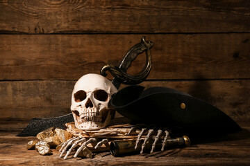 Human skull with old manuscripts, travel equipment and golden nuggets on brown wooden background