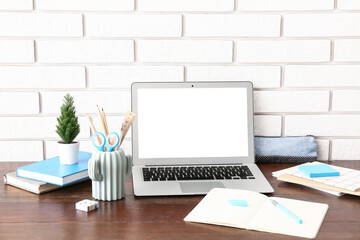 Modern laptop, houseplant and holder with different stationery on wooden desk
