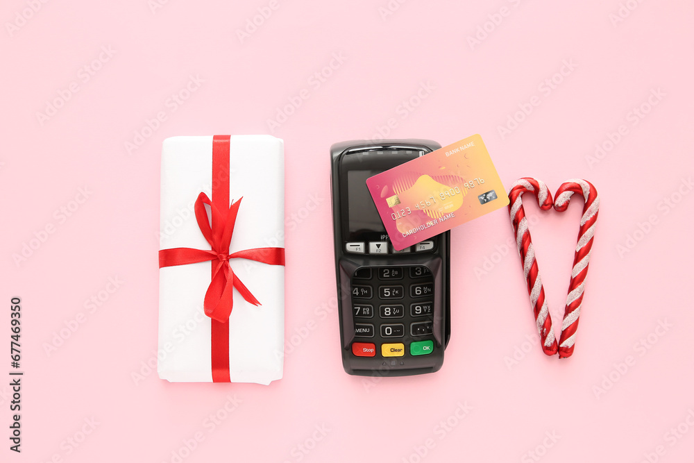 Sticker payment terminal with credit card, christmas gift box and candy canes on pink background