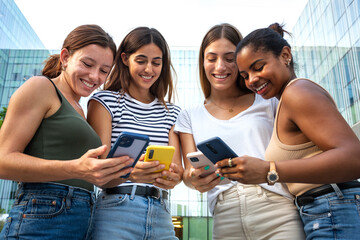 Group of happy multiracial college girl friend students looking at mobile phone.