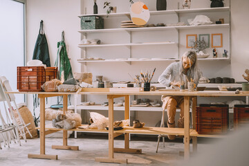 Woman creating clay product on ceramics workshop in art studio. Craftsperson on pottery workshop.