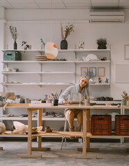 Woman creating clay product on ceramics workshop in art studio. Craftsperson on pottery workshop.