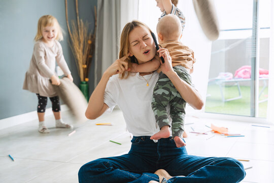 Woman alone with three children at home solving problems using phone.