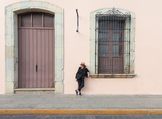 Fototapeta na wymiar A woman wearing a white hat poses against a barred window - Oaxaca, Mexico