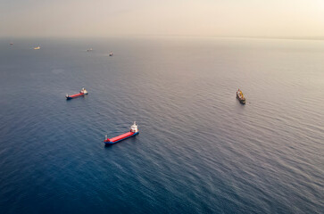 Many container ships at sea - Aerial image. Drone shot of red boats sailing at misty horizon background. Concept of transportation and logistics. Ship with cargo near Haifa shore, Mediterranean sea