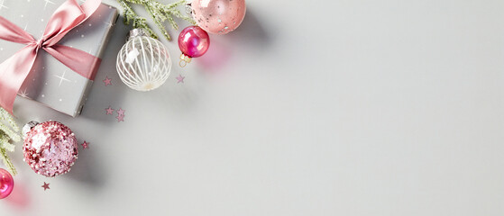 Elegant Christmas composition with festive present, pink ribbon, and glittering ornaments. Modern...