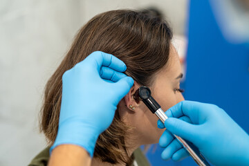 Advanced examination of a woman's ear using an otoscope at a doctor's appointment. - obrazy, fototapety, plakaty