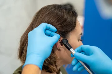 Foto op Aluminium Advanced examination of a woman's ear using an otoscope at a doctor's appointment. © RomanR