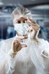 Surgeon woman doctor wearing uniform mask and gloves holding  blood at test tube in surgery clinic