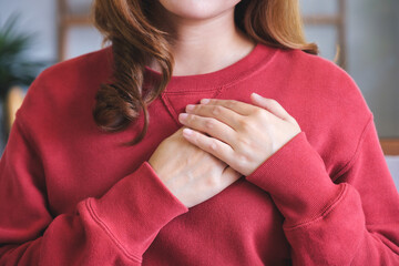 Closeup image of a happy young woman putting hands on her heart