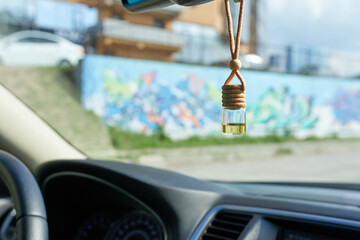 Car air freshener hanging on mirror, blurred background.