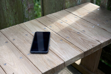 屋外で木のベンチに置かれたスマートフォン