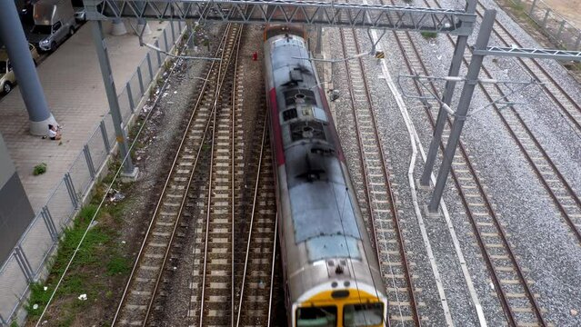 View from the top of a cargo train moving from the top to the bottom of the frame, passing by Bang Sue train station in Bangkok, Thailand.