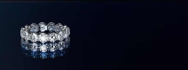 Eternity diamond ring on black glossy background. Wide image.