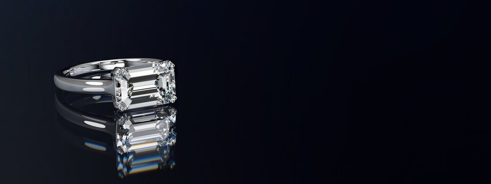 Emerald cut diamond ring on black glossy background. Wide image.