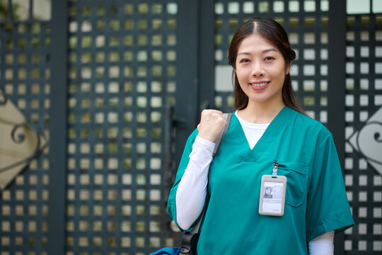 Portrait of smiling Vietnamese caregiver standing at gate of patients house