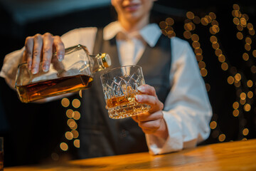 Bartender is pouring whiskey  glasses for customers beautiful night.