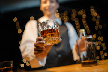 Bartender is pouring whiskey  glasses for customers beautiful night.