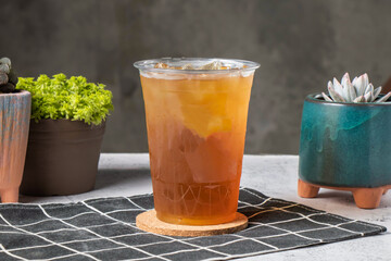 Meng Po tea served in disposable glass isolated on wooden board side view of taiwanese ice drink