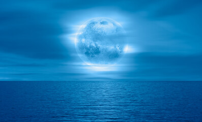 Naklejka na ściany i meble Night sky with blue moon in the clouds over the calm blue sea 