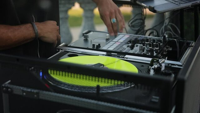 Close up of Wedding DJ man play and adjust controller with yellow vinyl