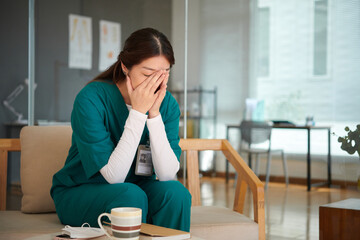 Medical nurse sitting on bench in lounge area and crying after loosing patient