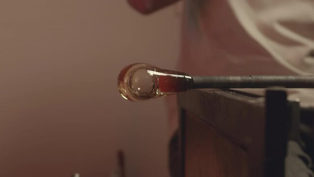Cropped shot of unrecognizable glassblowing craftsman molding shape of glass bubble on pipe in workshop