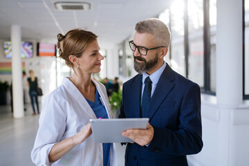 Pharmaceutical sales representative talking with female doctor in medical building. Hospital...