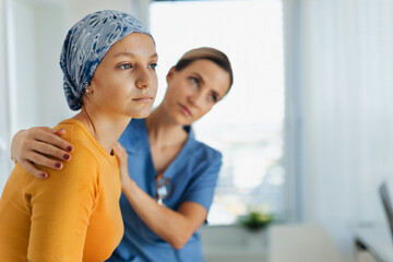 Teenage oncology patient talking with doctor. Oncologist treating teen girl with cancer and provide emotional support, helping her with anxiety and depression. - obrazy, fototapety, plakaty