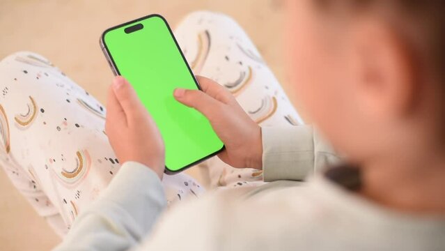 Children’s hands hold phone with green screen. Kid hold phone by two hands. close up green screen. 