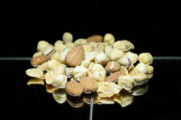 Dried nuts i. almonds, hazelnuts, pistachios. photo taken on a mirror, black background