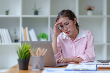 Young Asian businesswoman stressed by overwork at office. Beautiful Asian businesswoman stressed with work glitches in the office.