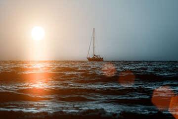 the sun rising over the sea and a lonely sailboat