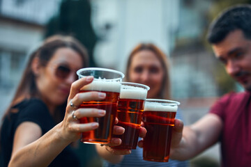 People holding beer cups and enjoying summertime outdoors.