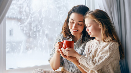 Mother and daughter enjoying winter nature in the  window - Powered by Adobe