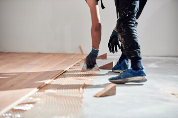 Professional handyman installing laminate flooring in a new apartment. - obrazy, fototapety, plakaty