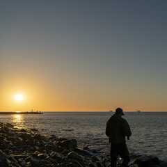 Fototapeta premium silhouette of a fly fisherman catching sea trout at dawn in the sea