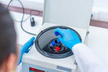 Scientist introducing blood samples in a centrifuge machine