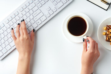 Female hands typing on kieyboard with coffee and cake on table