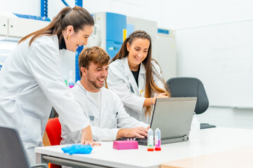 Smiling doctors using laptop in a cancer research laboratory
